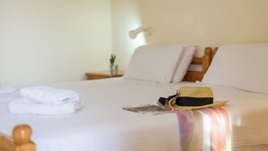 A neatly made bed with white linens, a folded towel, and a hat on the pillows. - Crete Essence Villas-Makrygialos (Ierapetra)