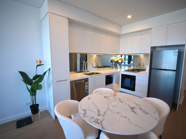 A modern kitchen with white cabinetry, a marble countertop, and a built-in oven.