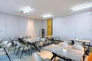 Une salle de conférence avec des tables et des chaises, un sol recouvert de moquette et un panneau de signalisation de sortie jaune.
