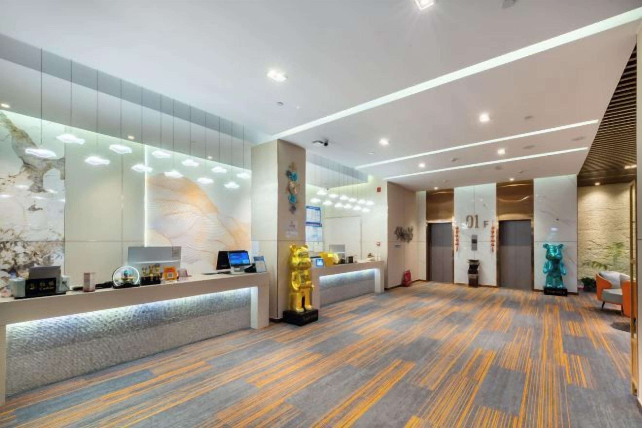A modern hotel lobby with a reception desk, a large golden statue, and a patterned carpet.
