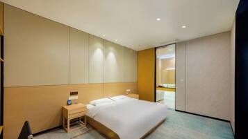 A hotel room with a bed, bedside table, and a desk with a chair.
