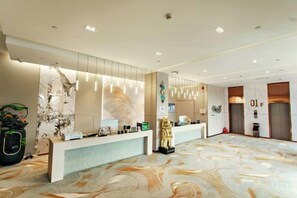 A hotel reception area with a marble floor, a reception desk, and a wall-mounted phone.