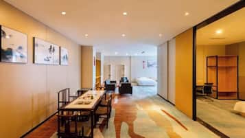 A hotel room with a dining area, a sofa, a bed, and a bookshelf.