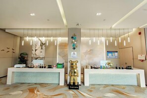 A hotel reception area with two reception desks, a central pillar, and a bear statue labeled 'Supreme.' - Lanyun jiduo Hotel (Tianjin)