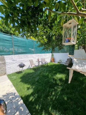 A backyard with a grassy lawn, a barbecue grill, and outdoor seating. - The Garden House in Paradisi (Rhodes)