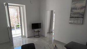 A modern living room with a marble coffee table, a flat-screen TV, and a sofa.