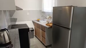 A modern kitchen with a stainless steel refrigerator, a coffee maker, and a trash bin.