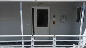 A white building with a door, a small window, and a security keypad.