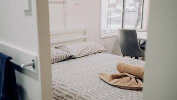 A small, compact room with a single bed, a chair, and a window.