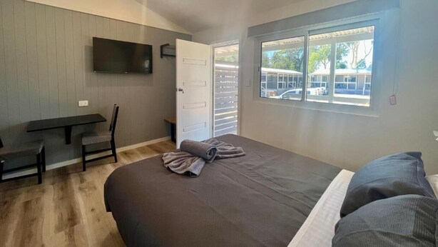 A bedroom with a bed, a desk, and a TV. - Westview Caravan Park - Dubbo (Dubbo)