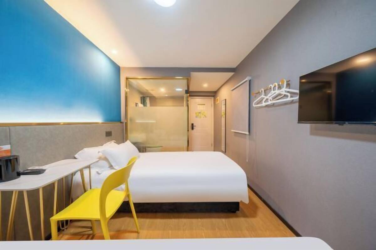 Ett hotellrum med en säng, ett skrivbord, en stol, en tv och en garderob.