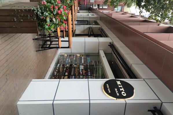 A hotel interior with a reception desk, a display of wine bottles, and a seating area with a wooden floor.