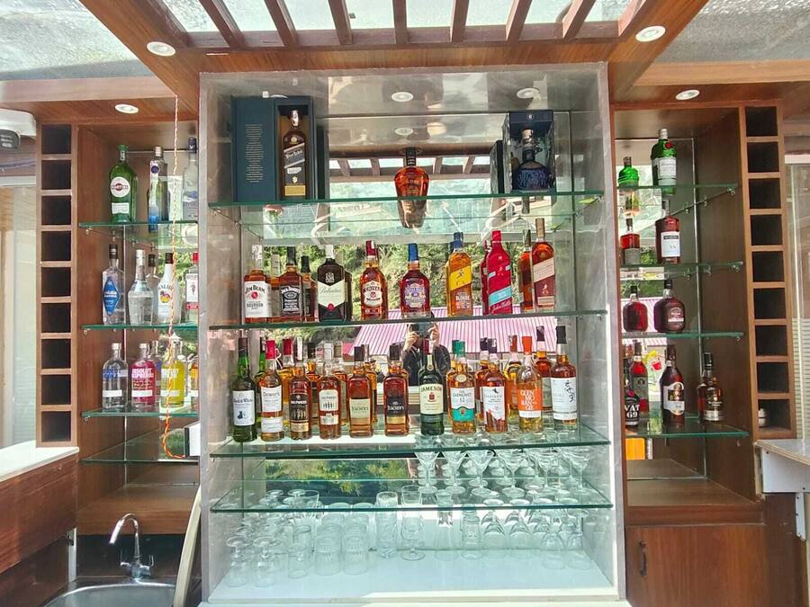 Zona de bar con varias estanterías llenas de botellas de licores y vasos.