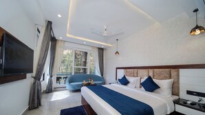 A modern hotel room with a large bed, a flat-screen TV, a ceiling fan, and a view of the outdoors. - Abhilashi Inn Kasol (Kasol)