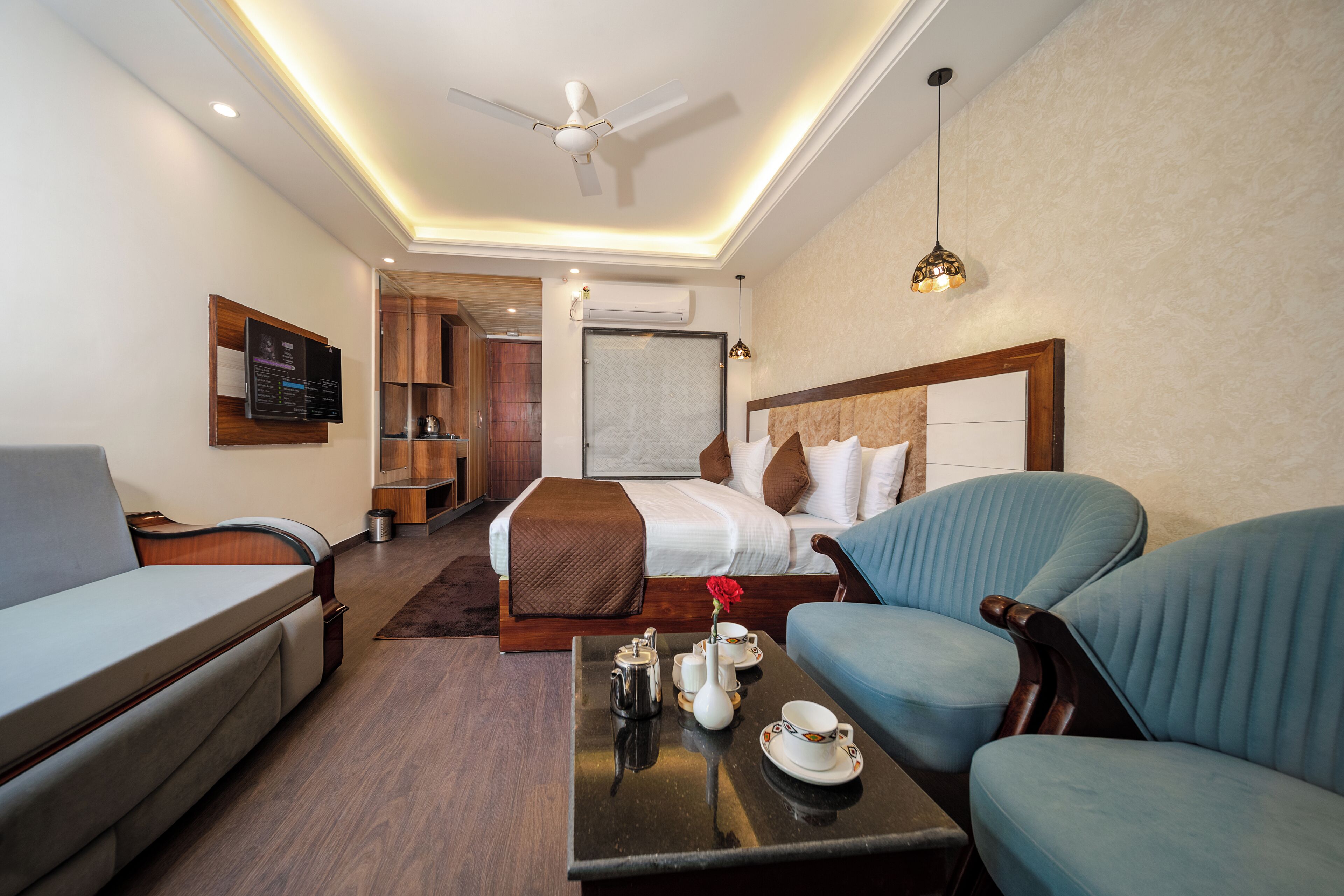 Una camera d'albergo con un letto, un divano, un tavolino da caffè e una televisione.