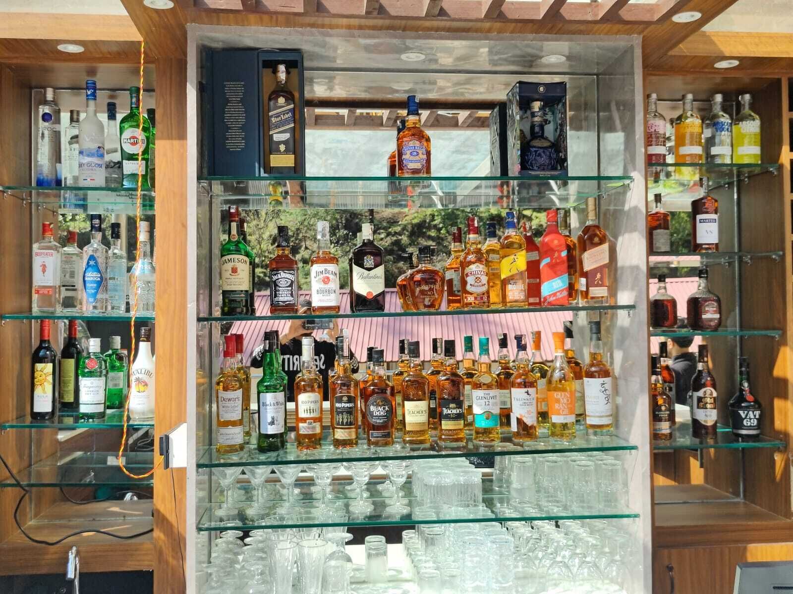 A bar area with multiple shelves stocked with various liquor bottles and glasses.