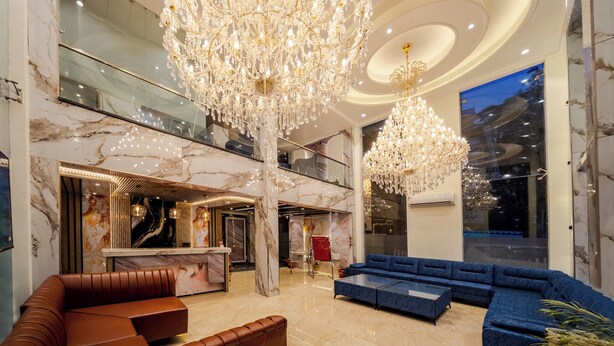 A spacious lobby with a grand chandelier, marble walls, a blue sofa, and a leather bench. - Abhilashi Inn Kasol (Kasol)