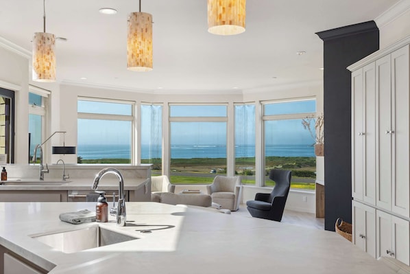 A modern kitchen with a large window, a sink, and a chair.