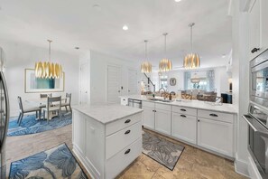 A modern kitchen with white cabinetry, a marble countertop, and pendant lighting. - New Downtime Prominence 30A Lux, Pet Friendly, LSV, Bikes (Panama City Beach)