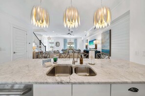Una cocina moderna con encimera de mármol, pileta de acero inoxidable e iluminación colgante.