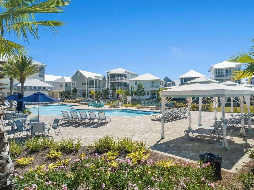 A pool area with lounge chairs and umbrellas, surrounded by buildings with a modern architectural style.