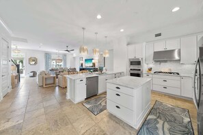 Una cocina moderna con armarios blancos, una isla central y electrodomésticos de acero inoxidable.