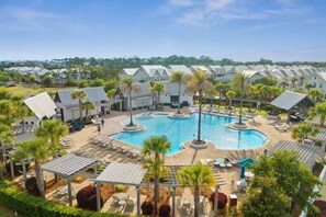 A resort with a central swimming pool, lounge areas, and a row of villas.