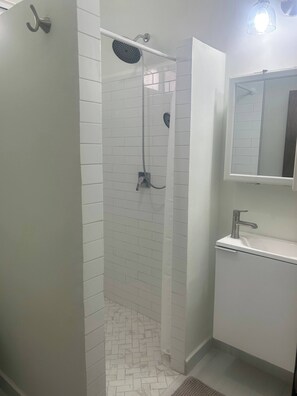 Ein Badezimmer mit Dusche, Waschbecken und Spiegel.