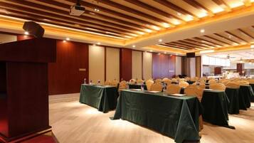 A conference room with tables set up for a meeting, a podium, and a large screen at the front.
