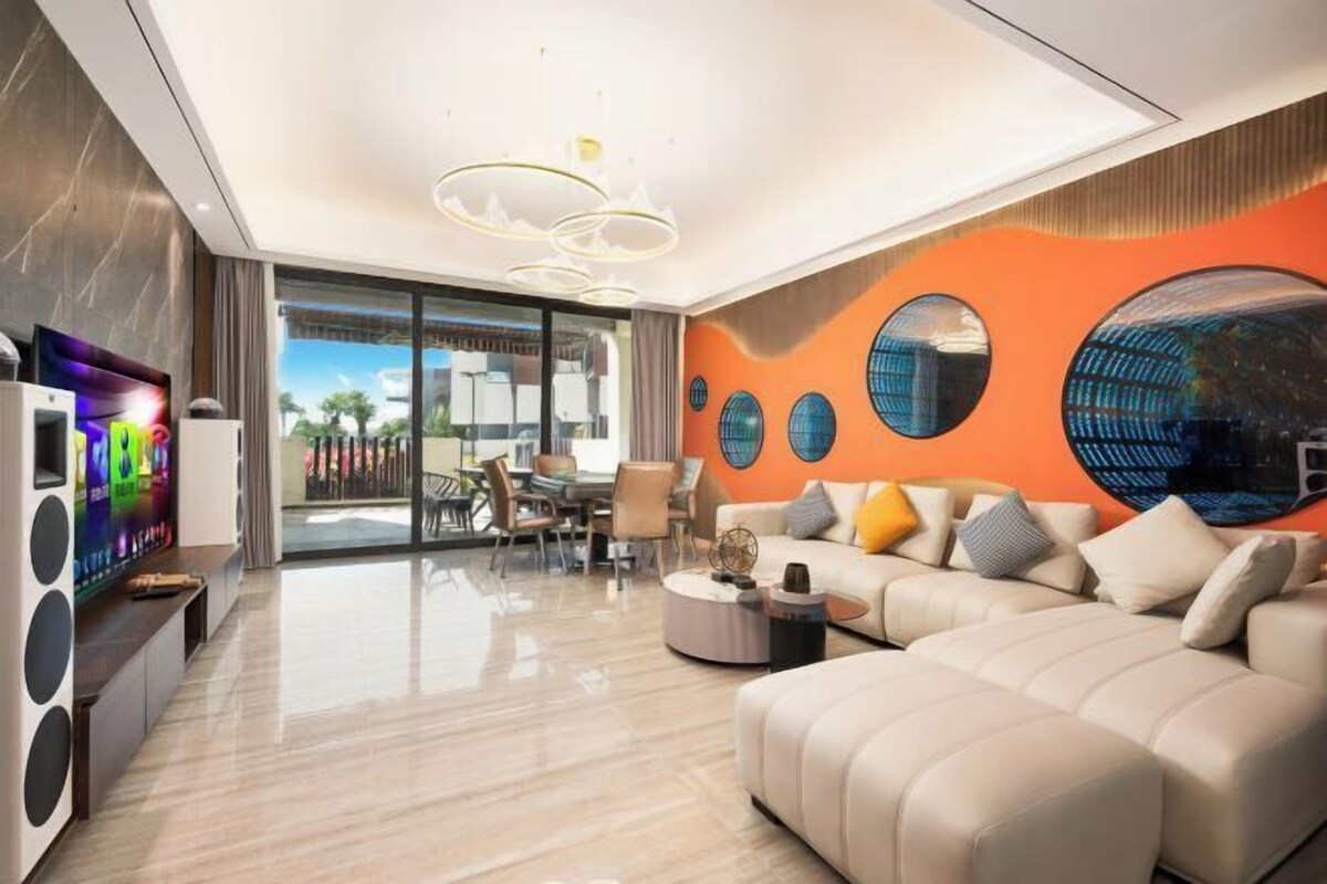 A modern living room with a flat-screen TV, a sofa, and a dining area with a table and chairs.