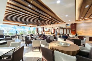 Un restaurante moderno con techos altos, paneles de madera y vista al océano.