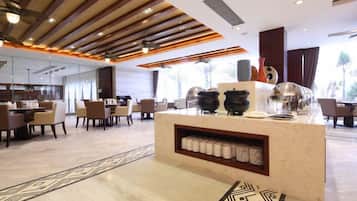 A modern hotel lobby with a central reception desk, seating area, and large windows.