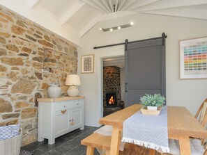 Una habitación acogedora con pared de piedra, chimenea, mesa de madera y un banco.