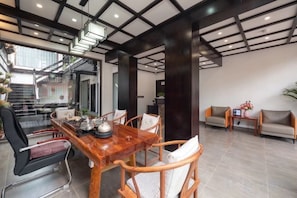 A modern interior with a wooden dining table, cushioned chairs, and a sofa. - Banmu Fangtang Inn in Lijiang (Lijiang)
