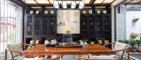 A dining area with a long wooden table, chairs, and a decorative ceiling.