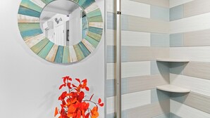 A bathroom with a circular mirror, wooden slat wall, and two shelves. - Bright Oceanfront Studio | Sleeps 4 w/ Pool Access (Ocean City)