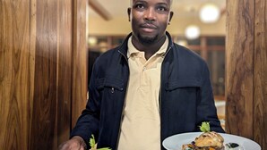 A person holding plates of food in a wooden interior. - Mvuli Mountain Lodge Ngorongoro (Karatu)
