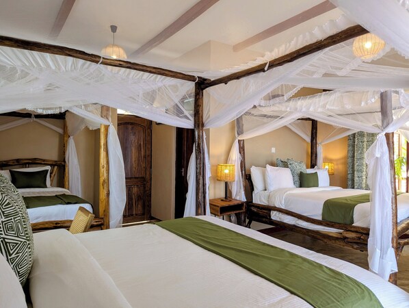 A room with two beds, each with a canopy bed frame and white bedding. There is a wooden door and a nightstand with a lamp. - Mvuli Mountain Lodge Ngorongoro (Karatu)