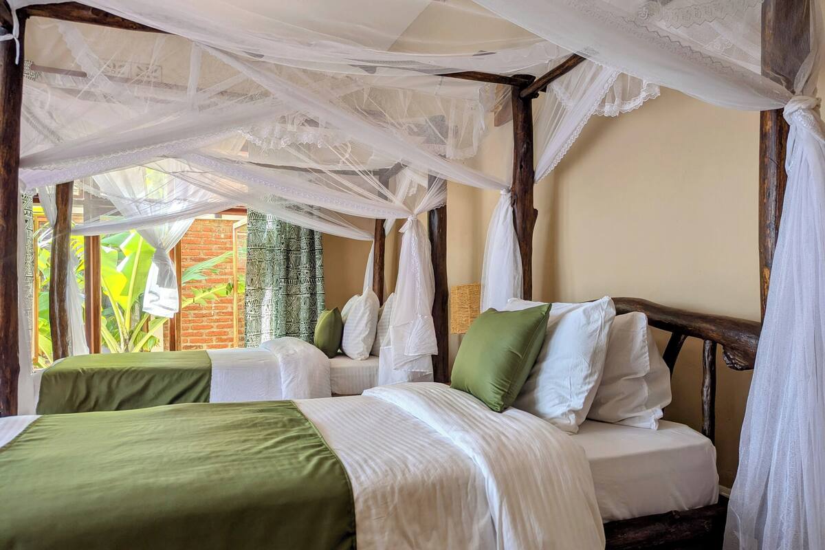 Una habitación con una cama bajo una dosel, una pared de ladrillo y una ventana con cortinas.