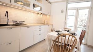 A modern kitchen with white cabinets, a stainless steel sink, and a dining area with a table set for two.