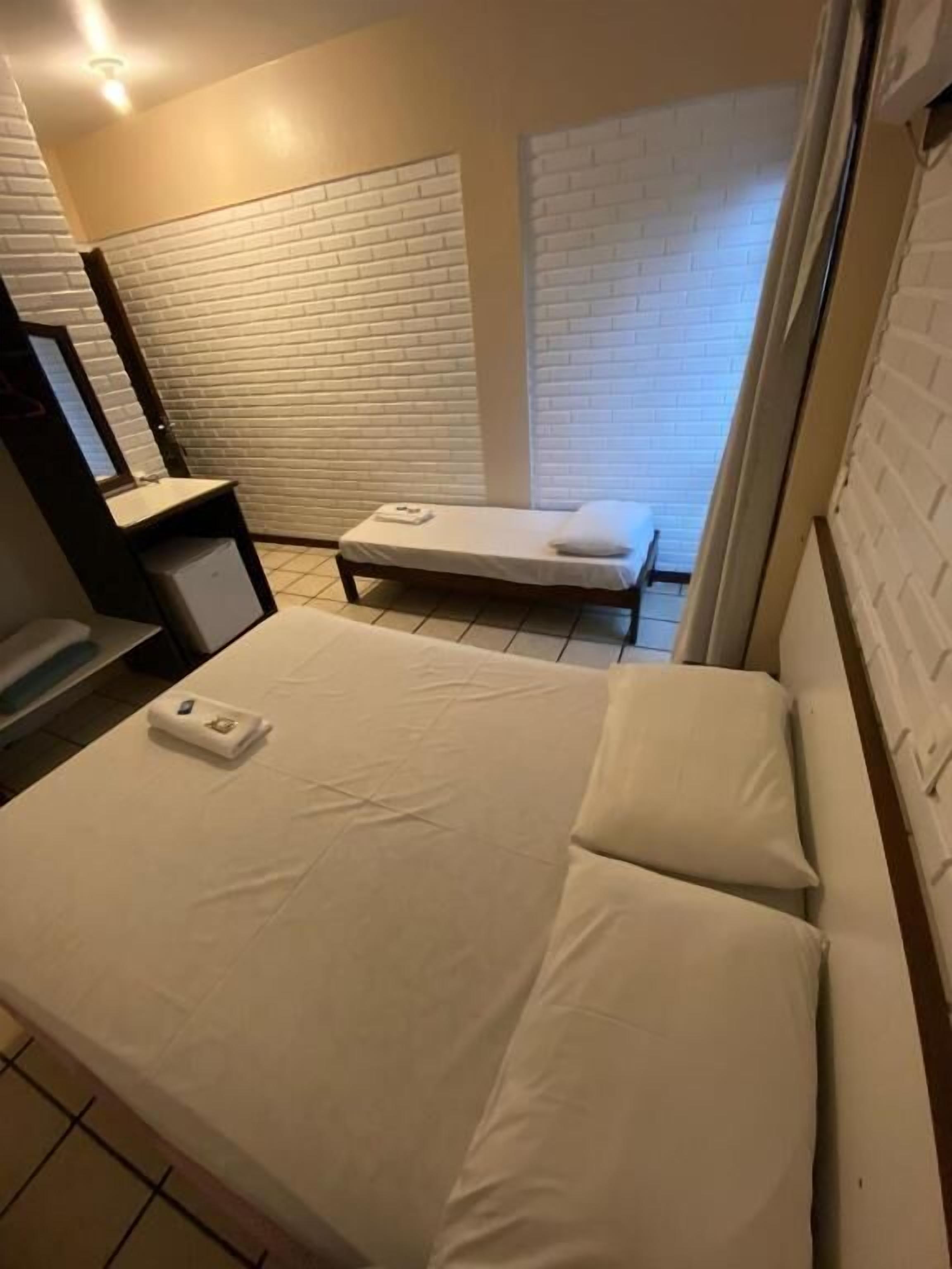 A hotel room with a bed, a small desk, a chair, and a window.