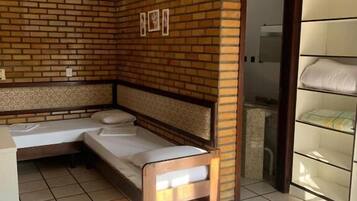 A room with a brick accent wall, a bed, a bench, and a wardrobe.