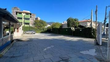 Un camino pavimentado que conduce a un edificio de fachada verde con un coche aparcado.