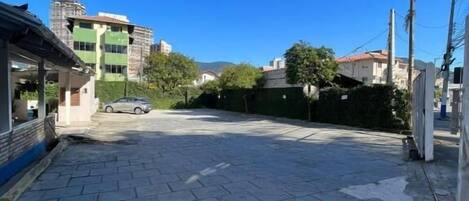 Un camino pavimentado que conduce a un edificio de fachada verde con un coche aparcado.