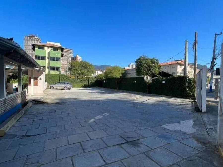 Un camino pavimentado que conduce a un edificio de fachada verde con un coche aparcado.