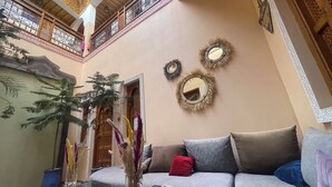 Una sala de estar con un sofá, espejos decorativos y una planta en maceta.