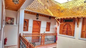 Un edificio de varios niveles con balcones de madera ornamentados, un techo con diseños y puertas tradicionales.