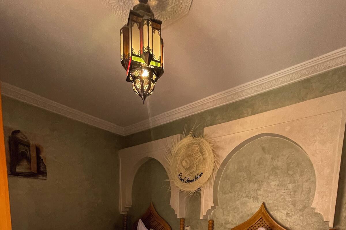 A hotel room with two beds, a decorative wall arch, a hanging lantern, and a patterned floor.
