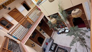 Un patio tradicional con una zona de estar central, una escalera y puertas y barandillas de madera ornamentadas.