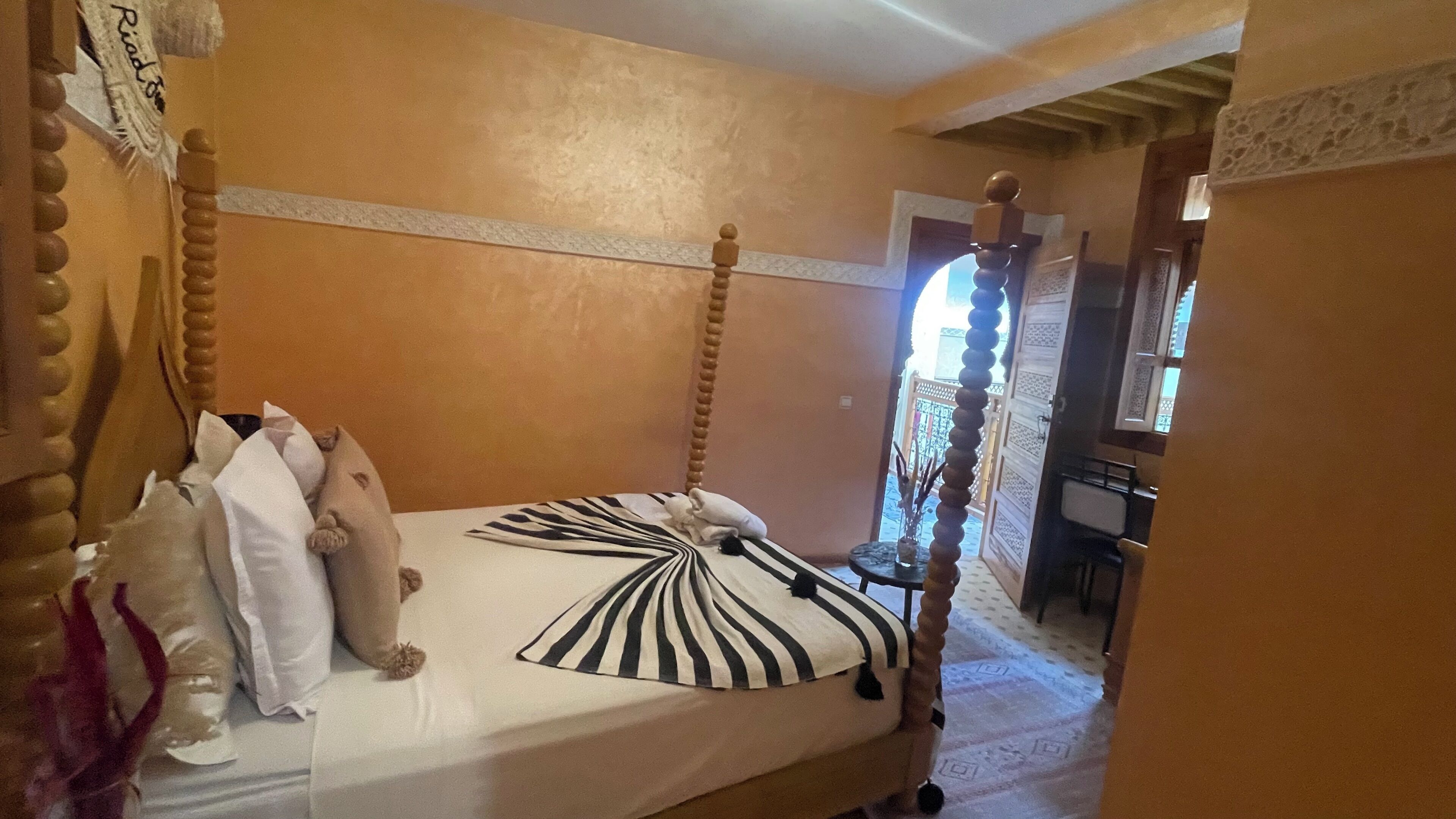 Ein Schlafzimmer mit einem Bett, Kissen, einem Nachttisch und einem Spiegel.